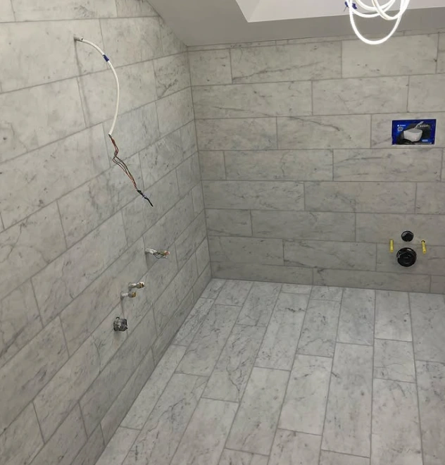 Badrum under renovering med nysatt marmorkakel på väggar och golv före montage